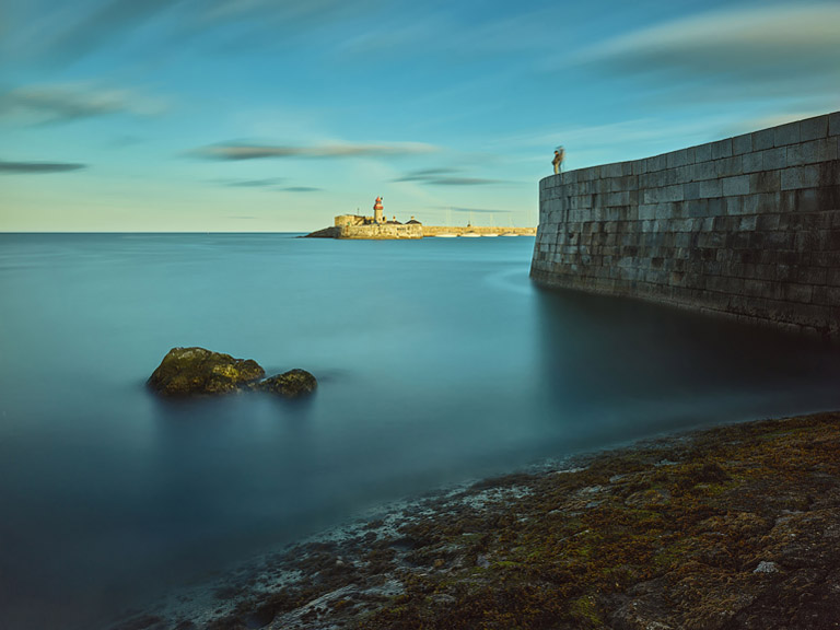 The Dun Laoghaire West Pier in the shadows, while the East Pier shines in the bright sunshine in the background.